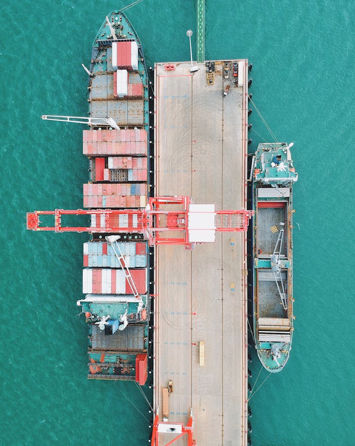 services-02 Aerial shot of cargo ships docked at a harbor with cranes and containers.